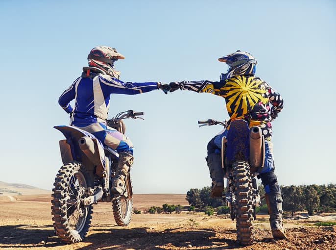 Motocross riders jumping through dusty terrain